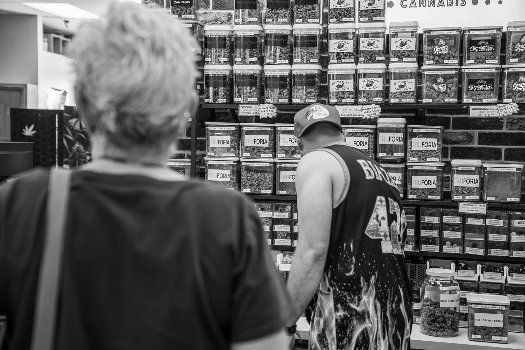 Black-and-white photo of a customer browsing the wall of flower jars