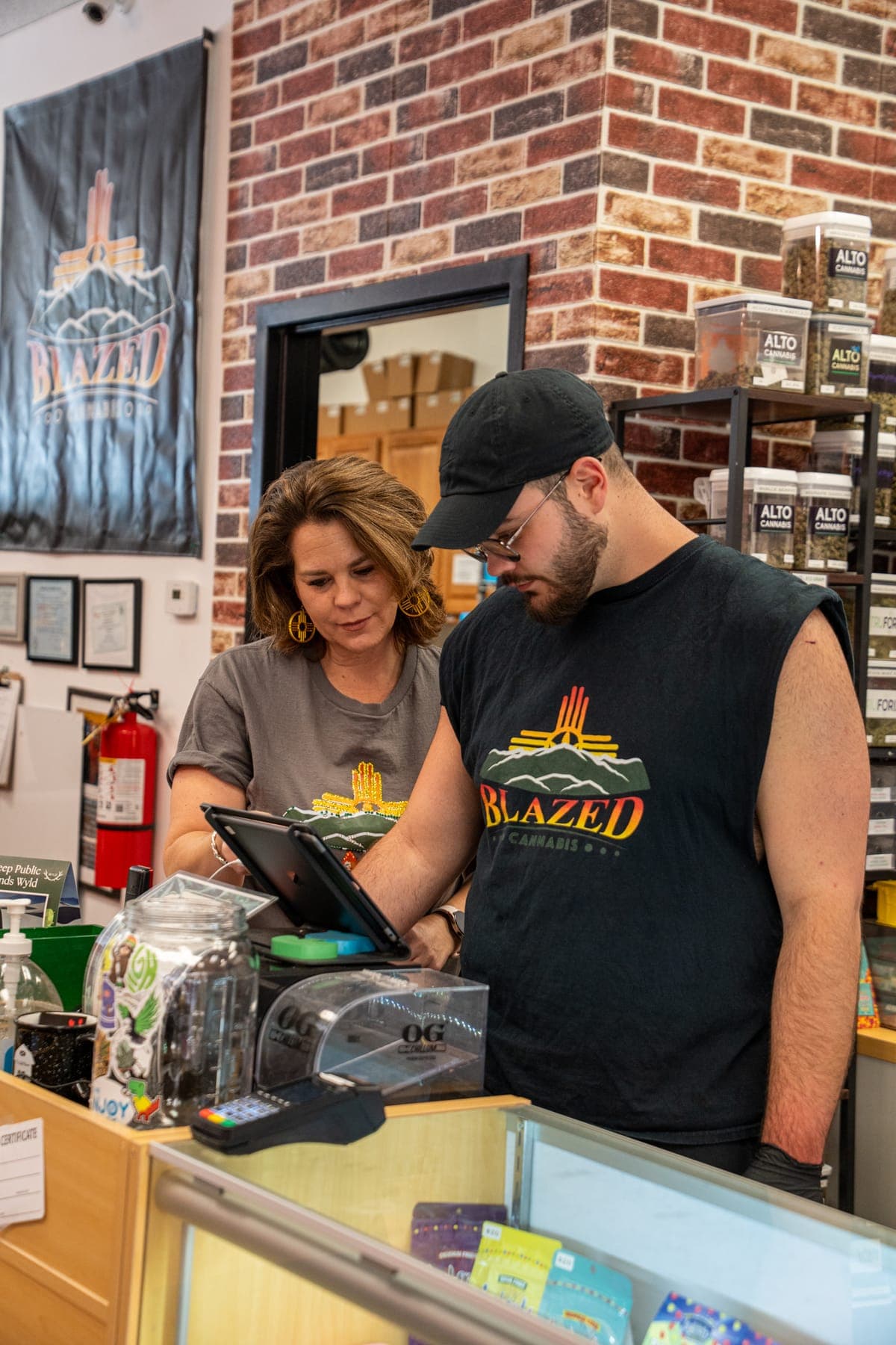 Mother and son working together at the register in front of the brick wall