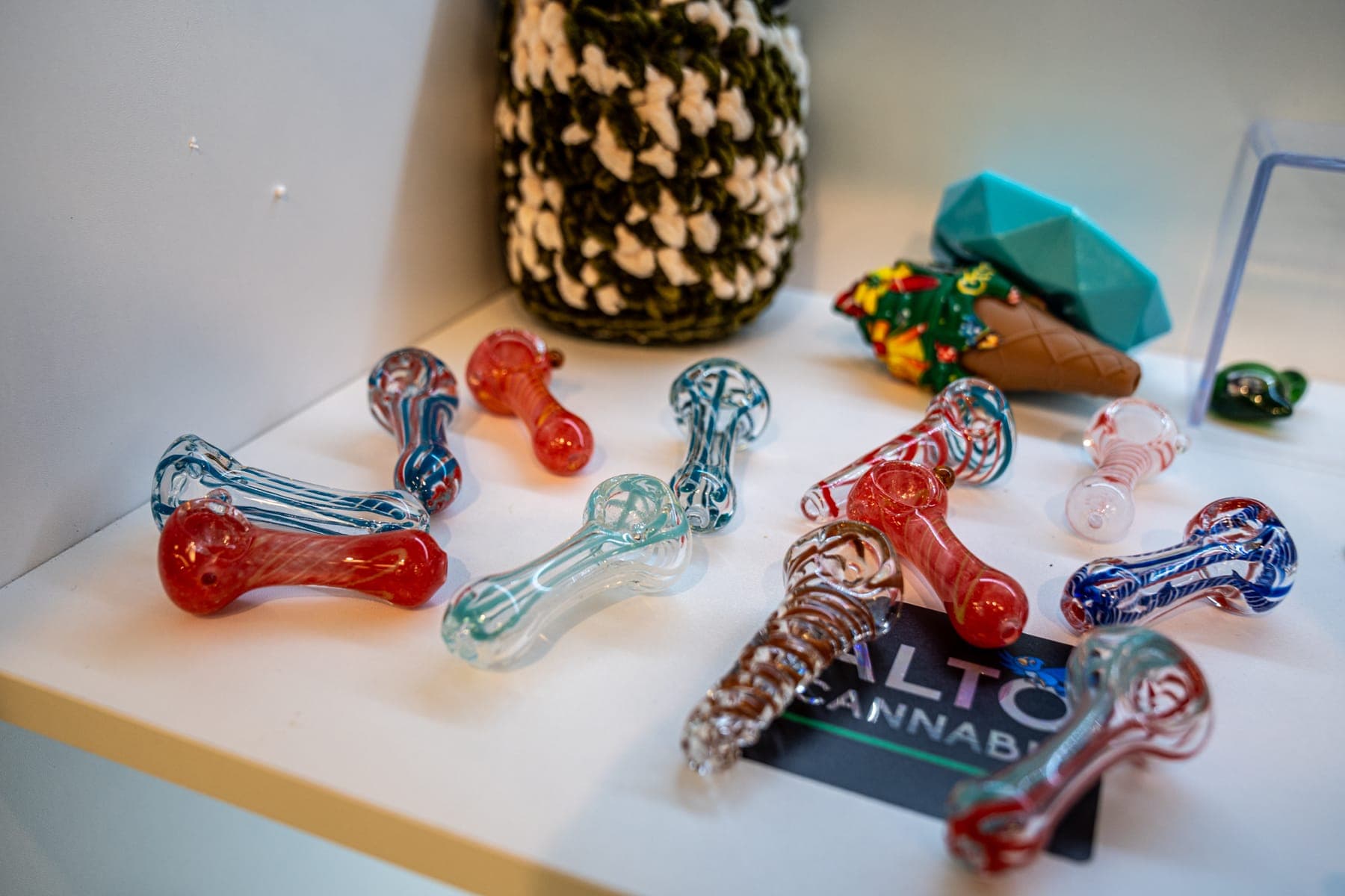 Colorful glass pipes laid out on a white shelf