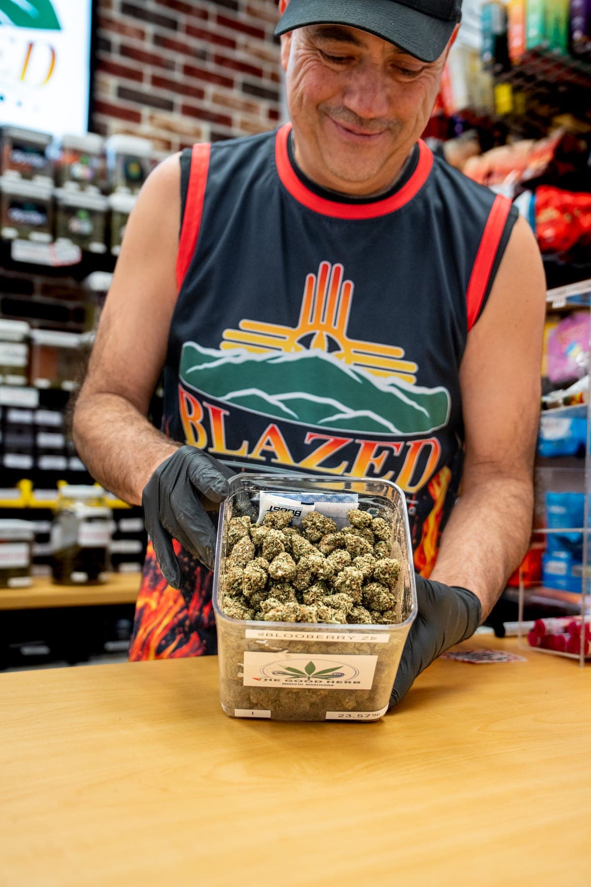 James holding up a clear tub of flower at the counter