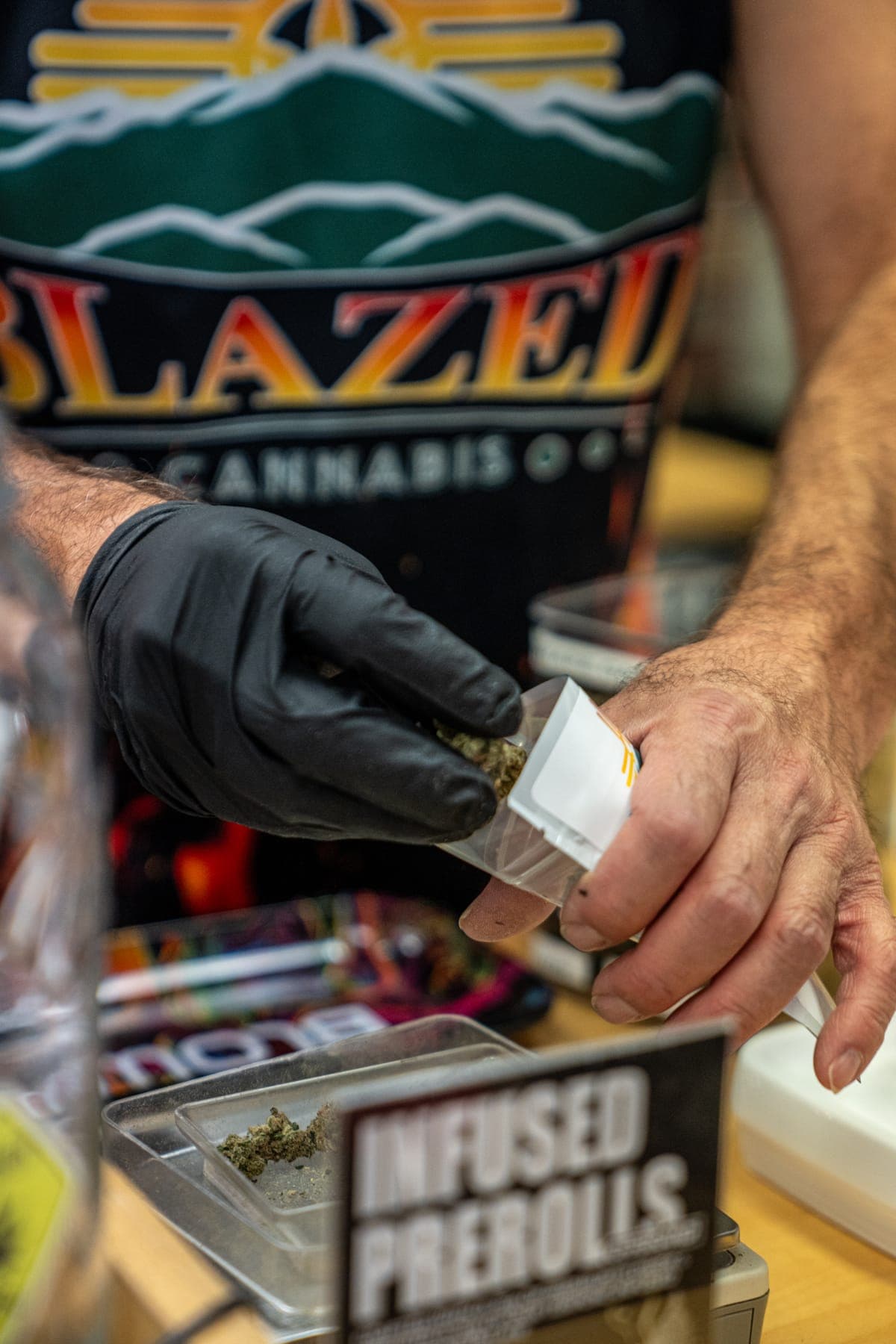 A gloved hand holding a pre-roll above the counter